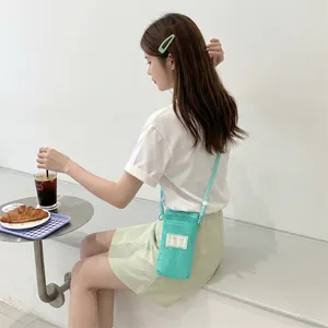 Detail of mint green mesh crossbody phone bag with woven strap on a white background