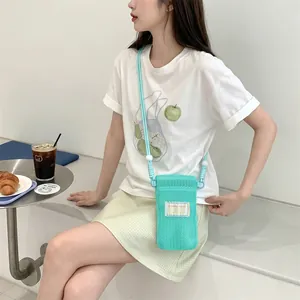 Crossbody phone bag in mint green mesh with adjustable rope strap on female model