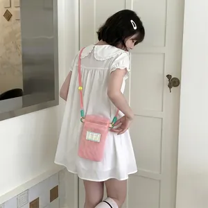 Close-up of pink mesh mobile phone bag with colorful rope strap and woven label