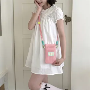 Pink mesh crossbody phone bag with contrasting neon buckles worn by model in white dress