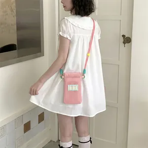 Pink mesh crossbody phone bag with woven strap and studio label detail on shoulder