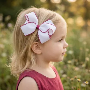 Handgefertigte weiße Haarschleife mit rosa Stickrand am Haar eines Kindes getragen