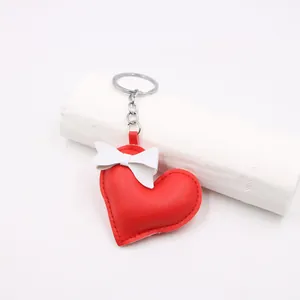 Detail of red faux leather heart pendant with white bow and silver keychain link