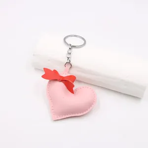Close-up of pink leather heart charm with red ribbon bow and silver metal keychain