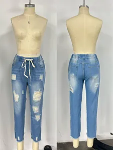 Detail of light blue ripped jeans showing elastic drawstring waist and frayed hem