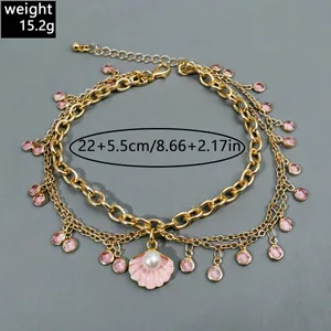 Detailed view of triple-layered gold anklet with pink crystals and pearl shell pendant