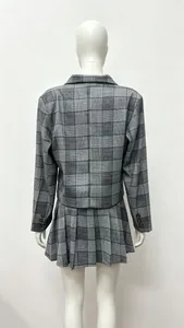 Macro detail of grey plaid blazer suit featuring pleated skirt and buttoned sleeve cuffs