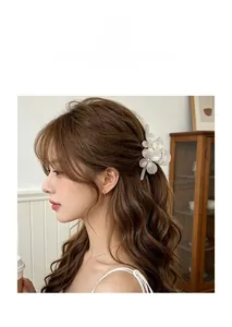 Détail de la pince à cheveux fleur blanche en acétate avec strass sur cheveux bouclés