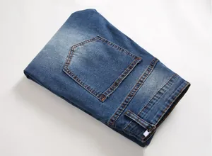 Close-up of dark blue denim jeans featuring orange contrast stitching and back pocket