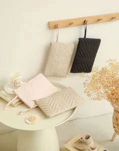 Detailed view of four quilted hanging toiletry bags in pink, beige, black, and khaki