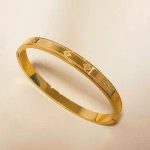 Gold-plated titanium steel lucky clover bangle with intricate engraved floral patterns