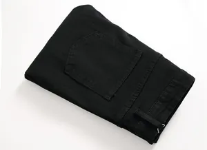 Detailed close-up of the back pockets and waist of folded black slim-fit denim jeans