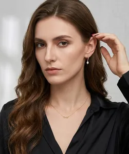 Primo piano di orecchini a goccia dorati e collana infinity sul collo della modella