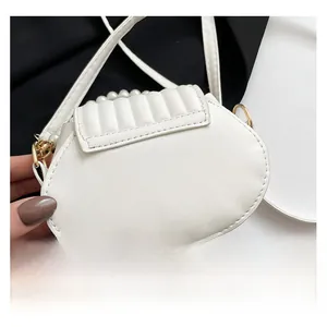 Gros plan du sac à main blanc avec poignée en perles, couture matelassée et boucles d'or