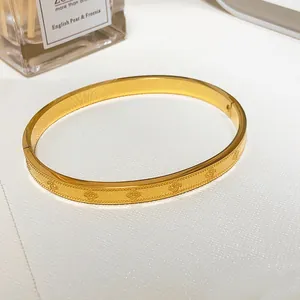 Detail view of a gold clover bracelet with embossed patterns and beaded texture edges