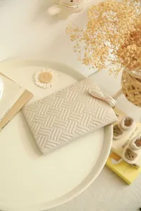 Close-up of beige quilted fabric toiletry bag with grid texture on a minimalist tray