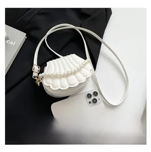 Détail du mini sac blanc en forme de coquille montrant la taille par rapport au téléphone