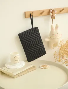 Close-up of a black quilted chevron handbag with a handle hanging in a cozy setting