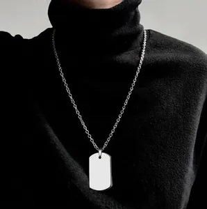Detail of silver rectangle dog tag pendant on a slim chain worn with black sweater