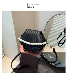 Détail du sac à main noir en forme de coquillage avec poignée en perles