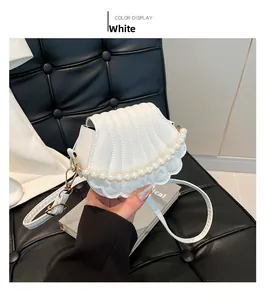Détail du sac à main blanc en forme de coquillage avec perles et boucles dorées