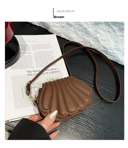 Détail d'un sac bandoulière marron en forme de coquillage avec poignée en perles