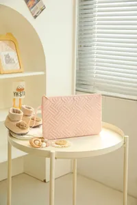 Pink quilted makeup bag with woven texture on a white table in a warm home setting