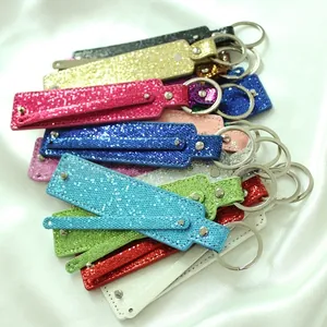 Close-up of colorful sequin keychains with metallic rings on white satin fabric