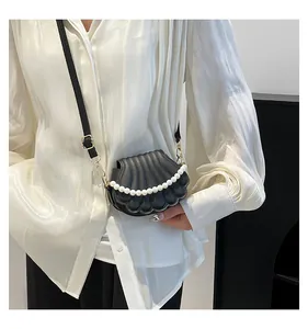 Gros plan du sac bandoulière en forme de coquillage avec cuir noir texturé et perles