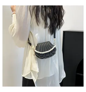 Détail du sac bandoulière noir en forme de coquillage avec texture matelassée et perles