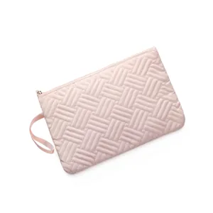 Detail view of pink quilted geometric cosmetic bag with smooth metal zipper and strap