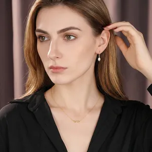 Eleganti orecchini s925 dorati con perle bianche e collana infinito su una modella