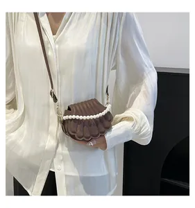 Vue détaillée d'un sac marron en forme de coquillage avec poignée en perles et bandoulière