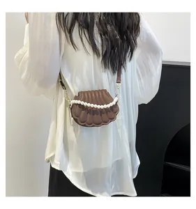 Détail du sac marron en forme de coquillage avec poignée en perles et bandoulière en cuir