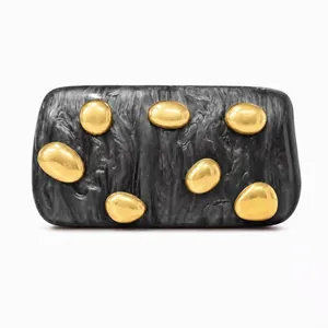 Detail of marble textured acrylic clutch with decorative golden pebble embellishments