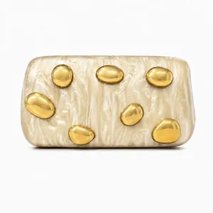 Detailed close-up of ivory marble acrylic clutch with gold pebble metal decorations