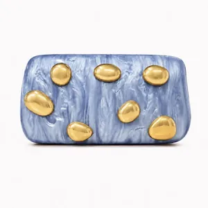 Detailed macro of marble acrylic clutch bag featuring organic golden metal decorations