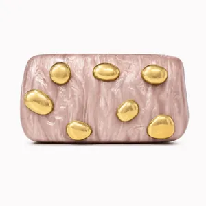 Detail of pink marble acrylic clutch with golden pebble-shaped metal decorations