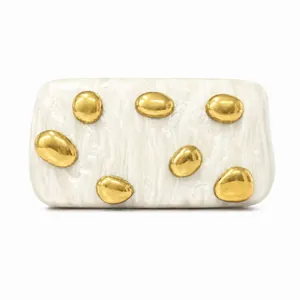 Detail of white marble acrylic clutch featuring gold pebble-shaped metal accents
