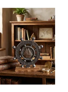 Detail of vintage nautical ship wheel decor with gold sail boat on a wooden desk