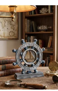 Close-up of vintage nautical helm sculpture with ship relief on a wooden desk