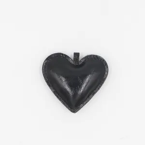 Vue détaillée du porte-clés coeur en cuir noir avec coutures et texture brillante