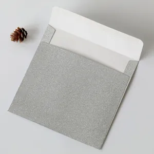 Macro shot of square silver glitter envelope with pine cone for luxury invitations