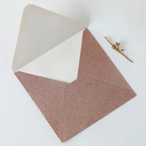 Macro detail of rose gold glitter envelope texture with white insert card
