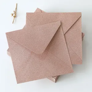 Macro detail of rose gold glitter envelopes with elegant triangular flap design