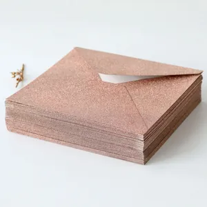 Close-up of stacked rose gold glitter square envelopes with premium metallic finish