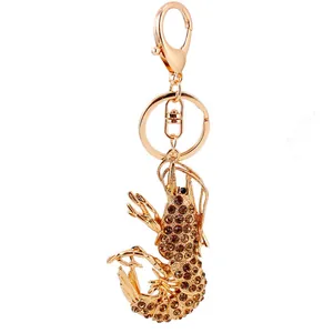 Sparkling lobster keychain in gold finish with champagne rhinestones on white background