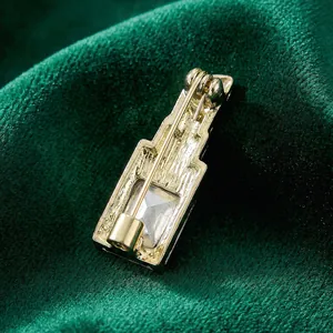 Élégante broche rouge à lèvres dorée avec cristal sur fond de velours vert foncé