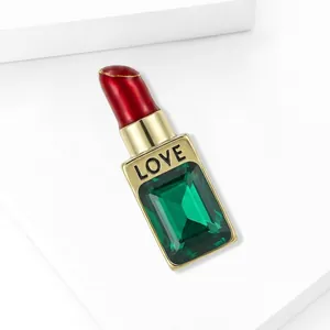Broche rouge à lèvres élégante avec pierre vert émeraude et gravure dorée