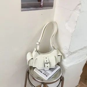 Detail view of cream multi-pocket utility shoulder bag with silver buckle accents